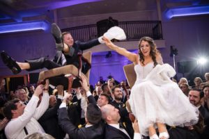 At the elegant estate at Florentine Gardens, a bride and groom are joyfully lifted into the air as part of the wedding celebration.