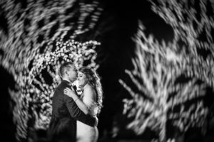 A bride and groom embracing in front of lights at the estate at florentine gardens.