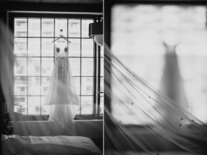 A wedding dress hanging in front of a window at a summer wedding.