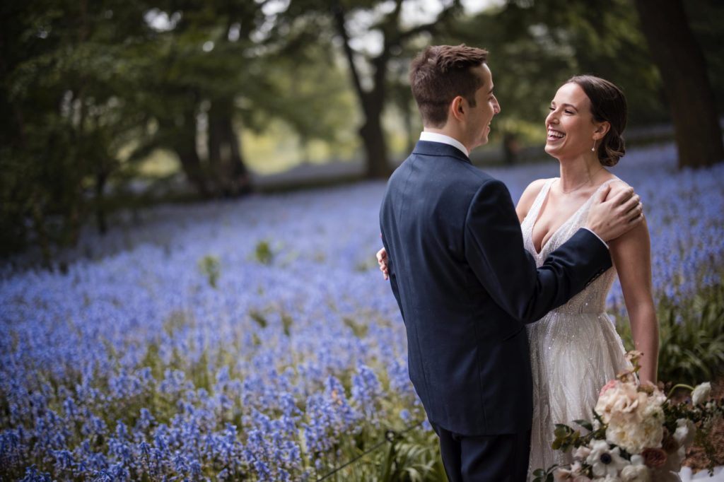 A rainy summer wedding with the bride and groom standing in a field of bluebells.