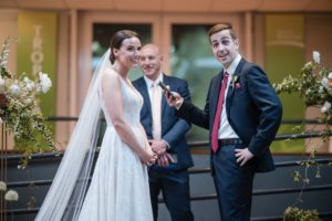 A bride and groom standing next to each other at a summer wedding ceremony.