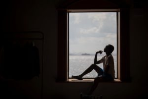 A person sitting in a window at the Liberty Warehouse overlooking the ocean during the summer.