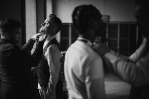 A black and white photo capturing the preparation of men for a summer wedding at the Liberty Warehouse.