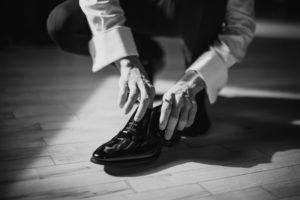 Black and white photo of a man tying his shoes at Liberty Warehouse during a summer wedding.
