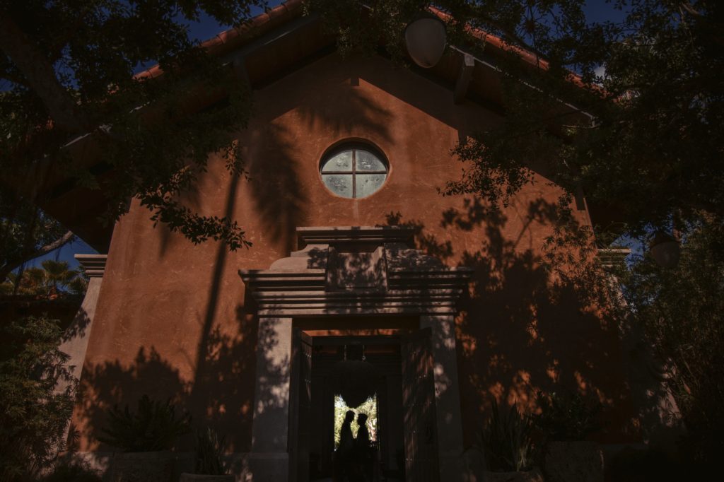A church with a doorway, surrounded by lush trees in the background.