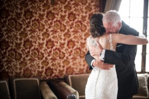 A bride and her father sharing an emotional hug before her summer wedding at the Bourne Mansion.