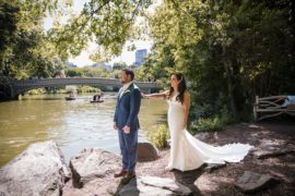 A bride and groom having their wedding ceremony next to a pond at the Wallace and Loeb Boathouse in Central Park.