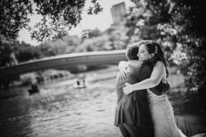 A wedding couple embracing at the Wallace and Loeb Boathouse with a river backdrop.