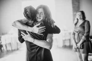 A man hugs a woman at a wedding in a black and white photo.