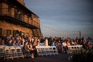 A summer wedding ceremony with white chairs on a rooftop overlooking the city at Liberty Warehouse.