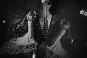 A summer bride and groom standing in front of a mirror at the Bourne Mansion.