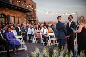 A couple celebrates their summer wedding at an outdoor ceremony, surrounded by the picturesque beauty of Liberty Warehouse.