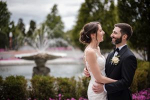 A summer wedding couple embracing in front of the Bourne Mansion fountain.