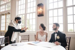 A bride and groom are sitting at a table during their summer wedding at the Bourne Mansion.