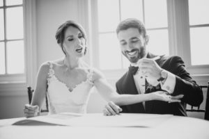 A black and white photo of a bride and groom at a table during their summer wedding at Bourne Mansion.