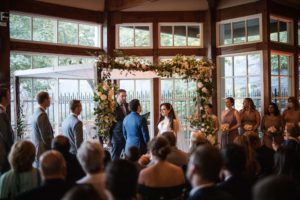 A wedding ceremony at Loeb Boathouse with windows overlooking the Wallace.