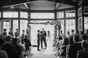 A black and white photo of a wedding ceremony at the Wallace and Loeb Boathouse.