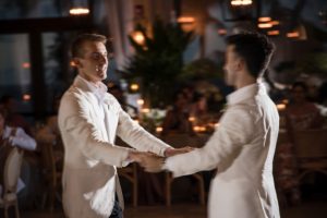 Two men in white tuxedos dancing at a wedding reception at the Ritz Carlton.