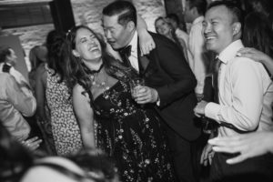 A black and white photo of a group of people dancing at a summer wedding.