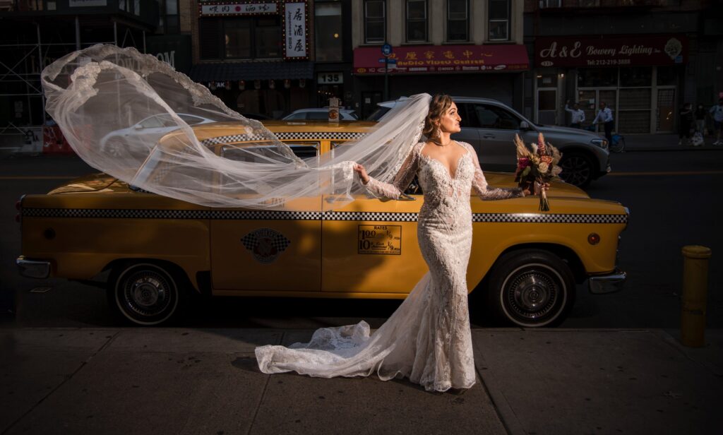 A bride poses in front of a yellow taxi in Capitale, NYC.