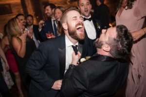 Two men laughing at a summer wedding reception held at Liberty Warehouse.