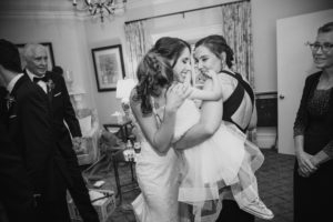 A bride hugging her daughter in a black and white photo taken during a summer wedding at the Bourne Mansion.