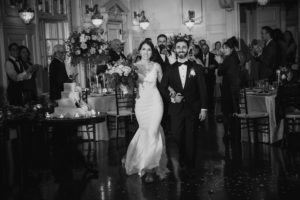 A summer wedding at Bourne Mansion captured in a beautiful black and white photo of a bride and groom walking down the aisle.