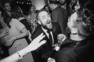 A black and white photo of a man having a good time at a Summer Wedding party at Liberty Warehouse.