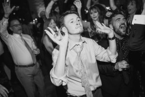 At the Liberty Warehouse, a man is joyfully dancing on the dance floor at a summer wedding.