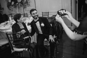 A man is capturing a moment of a woman at a summer wedding at Bourne Mansion.