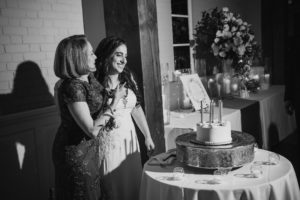 Two women standing next to a cake at a wedding in a black and white photo.