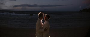 A wedding couple standing on the picturesque Dorado Beach at dusk.