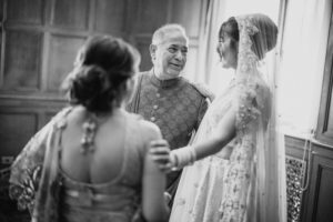An Indian bride and her father at their Gotham Hall wedding, sharing a heartfelt moment as they look into each other's eyes.