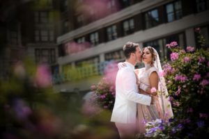 A wedding couple kissing in front of flowers at Gotham Hall.