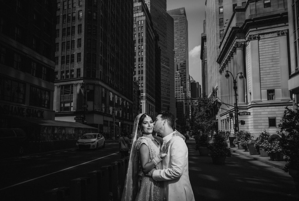 A bride and groom sharing a passionate kiss in the middle of a city street during their Gotham Hall Wedding.
