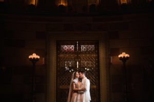 A Gotham Hall wedding with a bride and groom kissing in front of the ornate building.