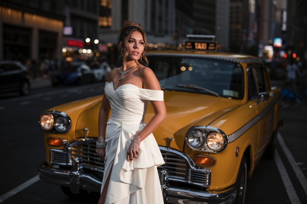 A bride poses in front of a Gotham Hall taxi cab in New York City.
