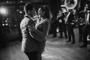 A black and white photo of a couple dancing at their wedding in front of a band.