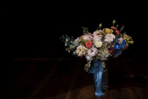 A summer wedding bouquet of flowers sitting on a wooden floor.