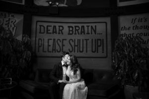 A bride and groom sitting in front of a **wedding** sign at **501 Union** in **Brooklyn**, that says "dear brain please shut up.