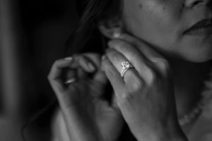 A black and white photo of a woman wearing a wedding ring at Riverside Farm during a summer wedding.