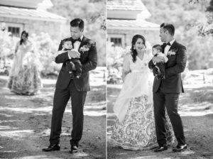 A man in a suit and a woman holding a baby at a summer wedding.