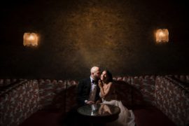 A wedding couple sitting on a couch in a dark room at the 74 Wythe venue.