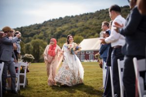 A bride walks down the aisle at a summer wedding at Riverside Farm.