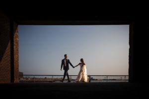 A bride and groom walking through an archway at sunset in New York for their wedding.
