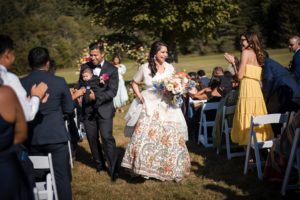 A summer wedding at Riverside Farm, with a bride and groom walking down the aisle.