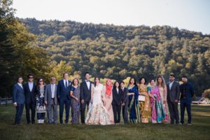 A group of people posing for a photo in a Riverside Farm during a summer wedding.