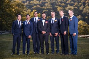 A group of groomsmen posing for a photo at Riverside Farm during a summer wedding.