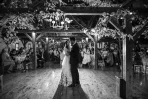 A couple celebrating their summer wedding at Riverside Farm share their first dance in a barn.