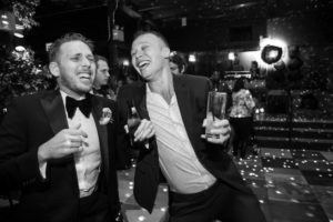 Two men in tuxedos laughing at a wedding party.